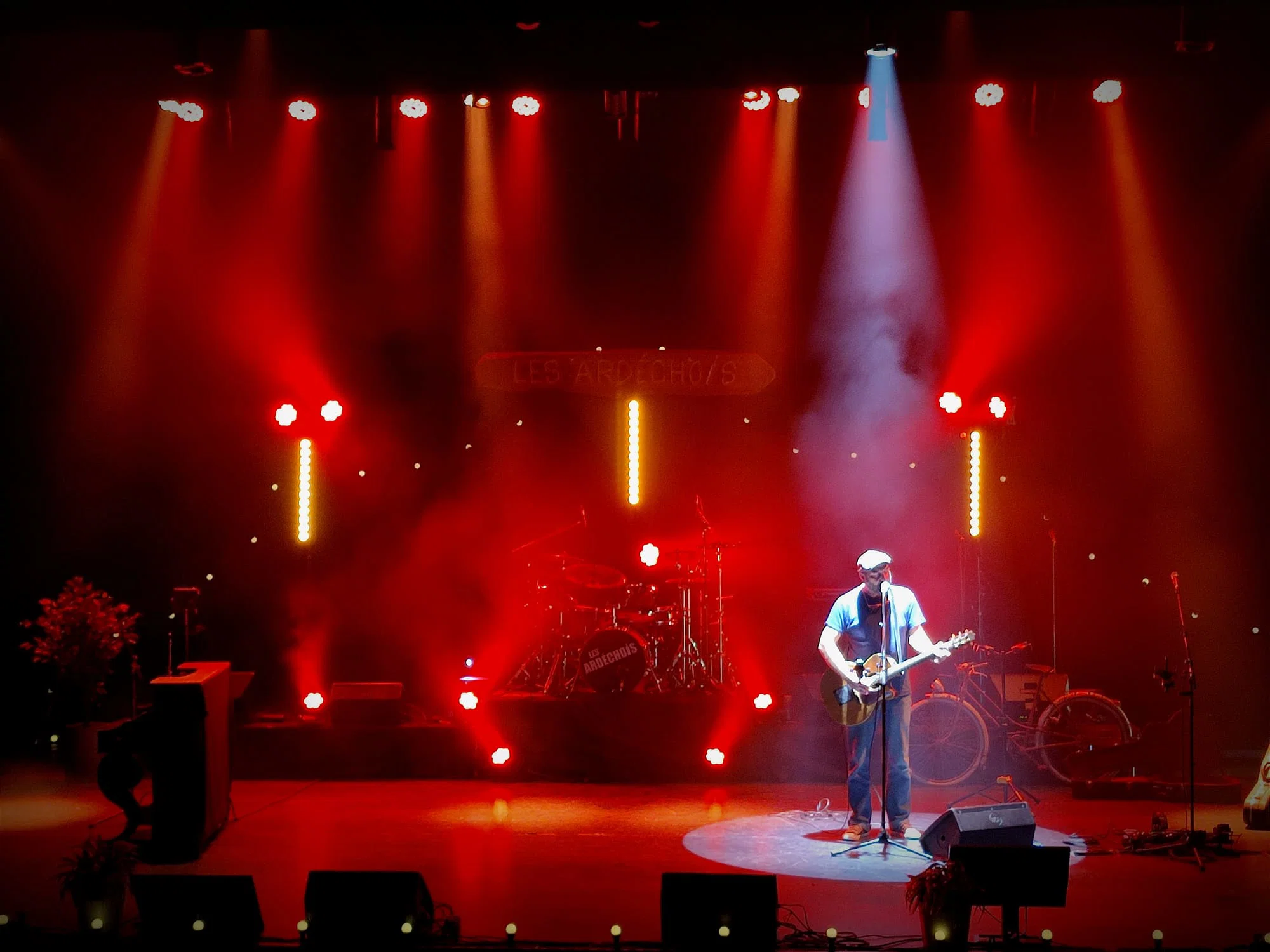 Concert éclairé en contre-jour rouge, douche blanche sur le chanteur